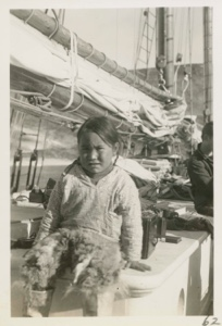 Image of Little Eskimo [Inuk] girl sitting on cabin (Etookashoo's daughter)